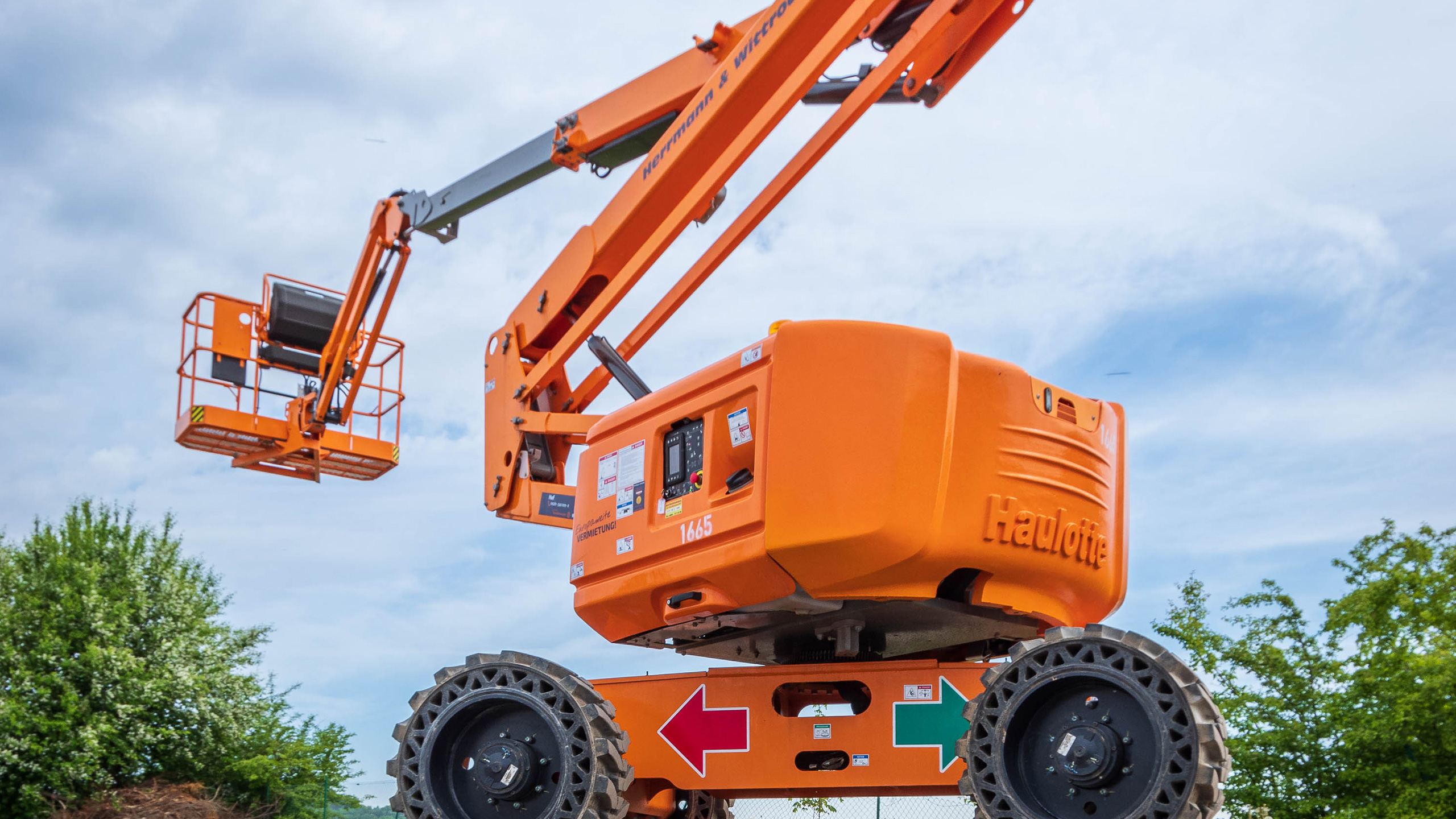 Im Bild eine orange Teleskopbühne, blauer Himmel mit leichten Wolken